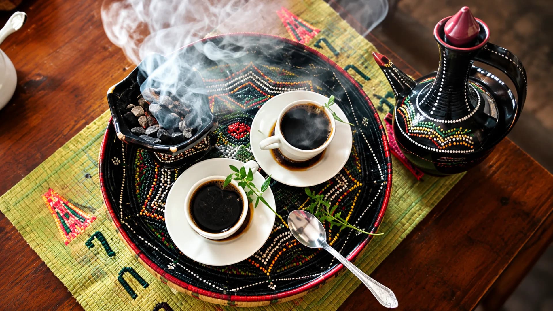 Hands pouring coffee from a traditional Ethiopian jebena during a coffee ceremony